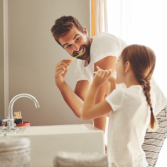 Father with daughter brush their teeth in their bathroom