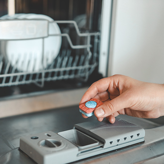 A woman puts a dishwasher tab in the dishwasher