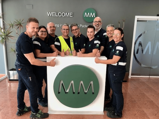 M Packaging Ibérica team standing at the plant entrance celebrates AA+ BRCGS certification after unannounced audit.